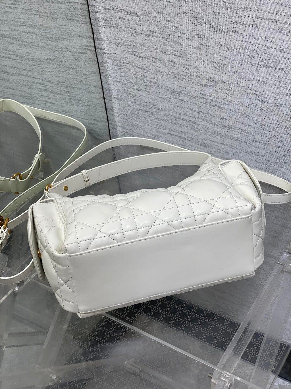 White quilted baguette crossbody bag with curved zipper top and slim strap