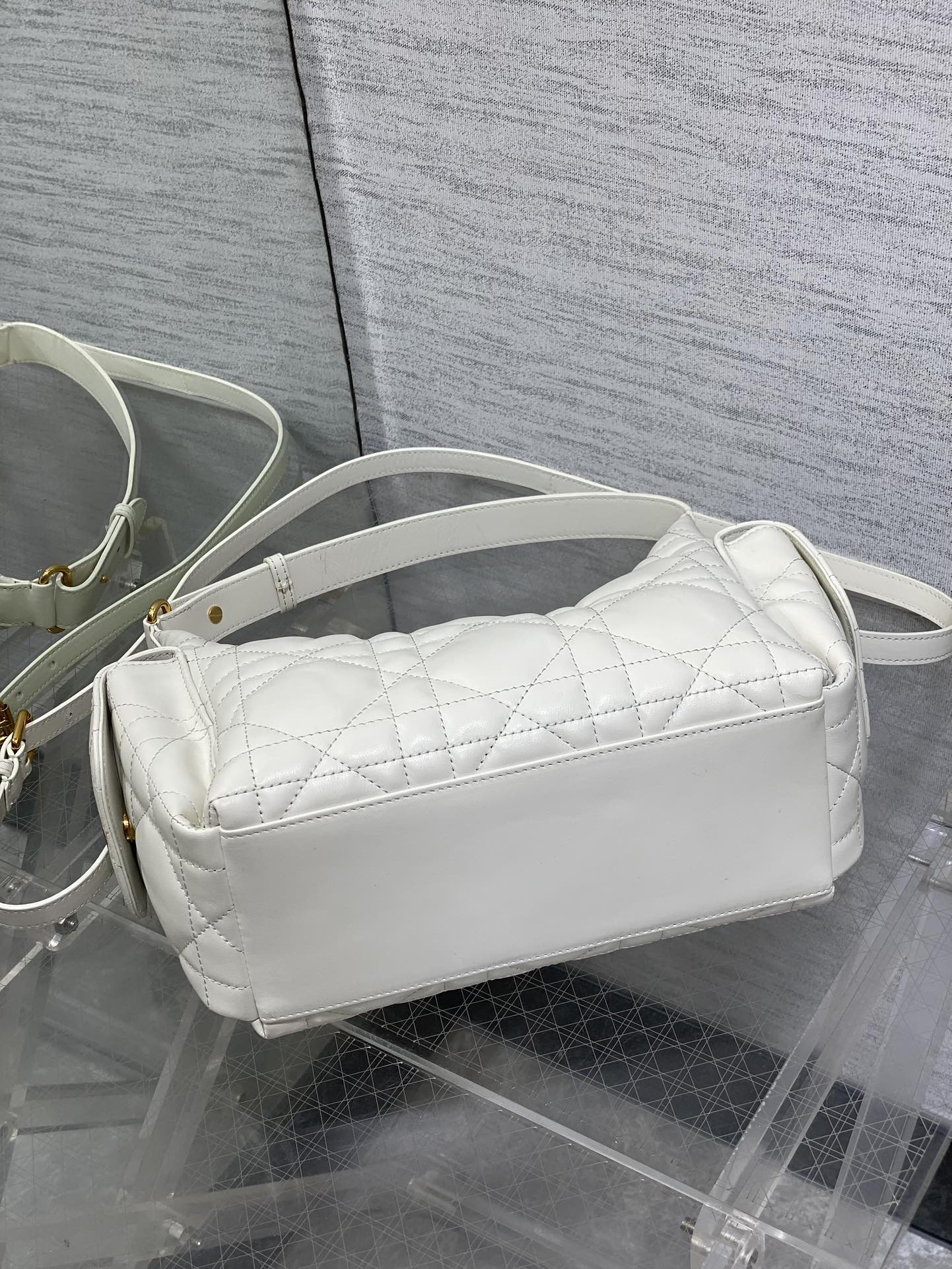 White quilted baguette crossbody bag with curved zipper top and slim strap