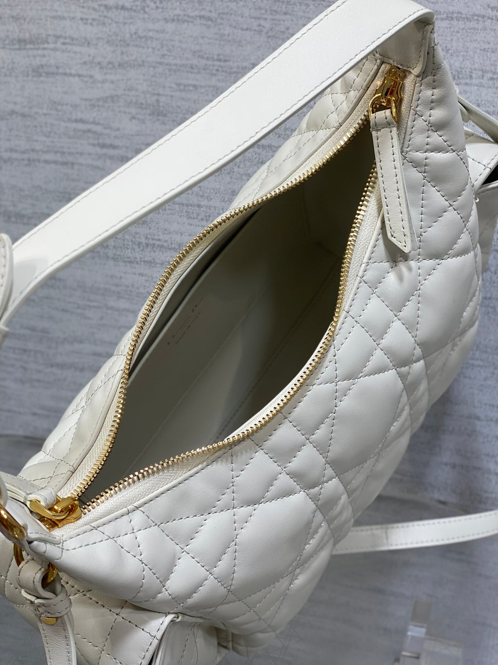 White quilted bag with zipper open to show dark green interior lining