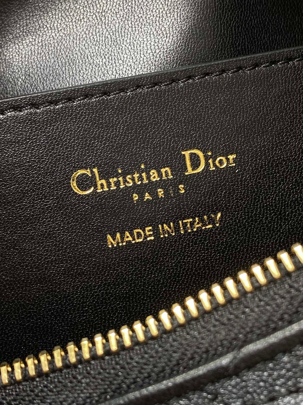 Leather bag label reading Christian Dior, MADE IN ITALY, near gold zipper