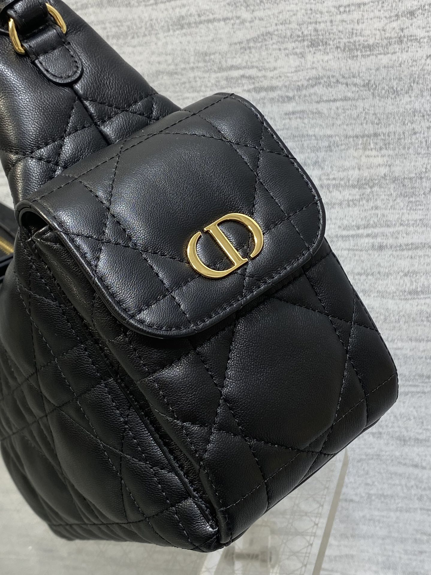 Dior bag detail: quilted black top flap with gold Dior emblem and snap closure
