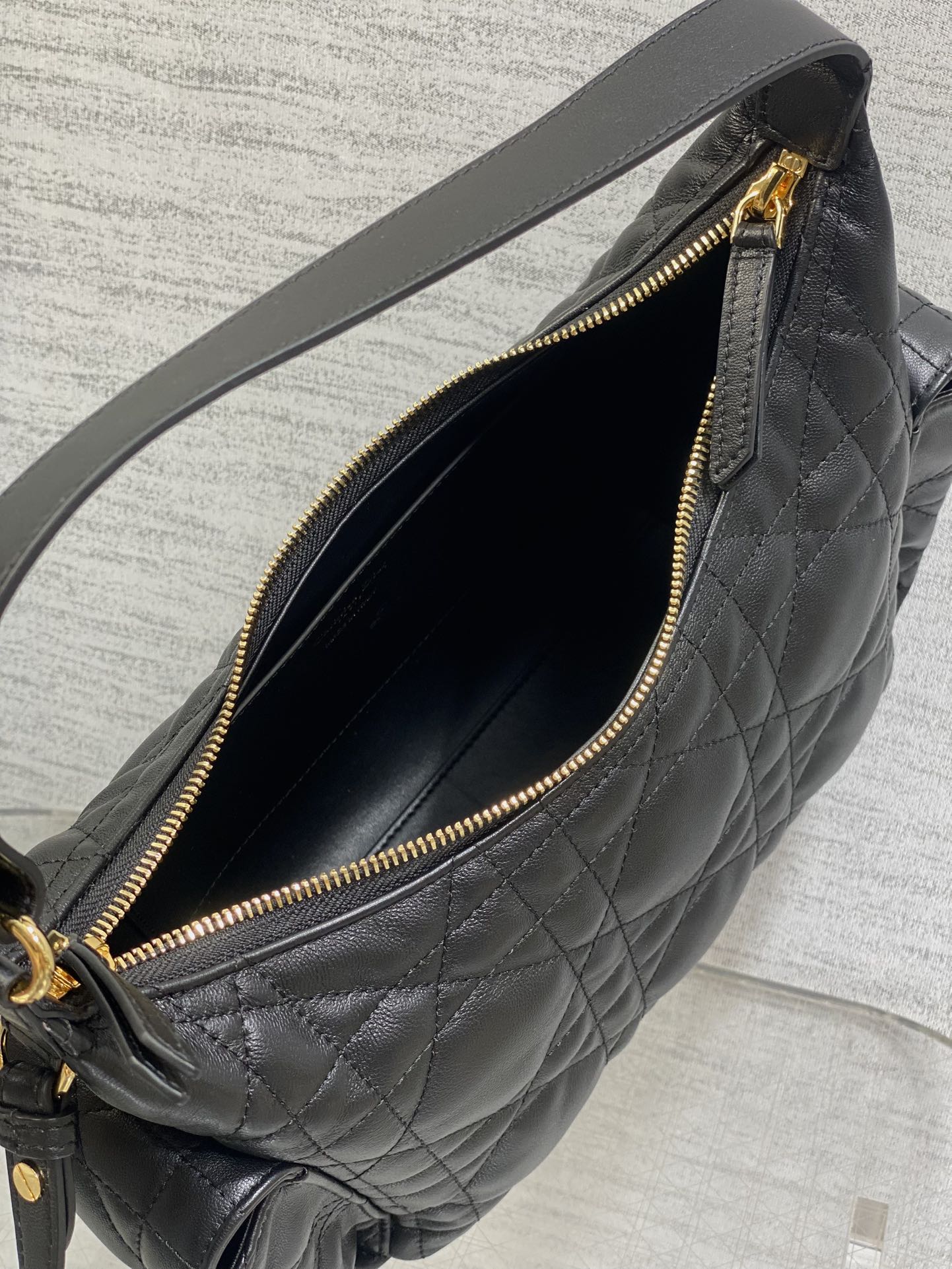 Black quilted bag interior close-up with gold zipper and dark fabric lining