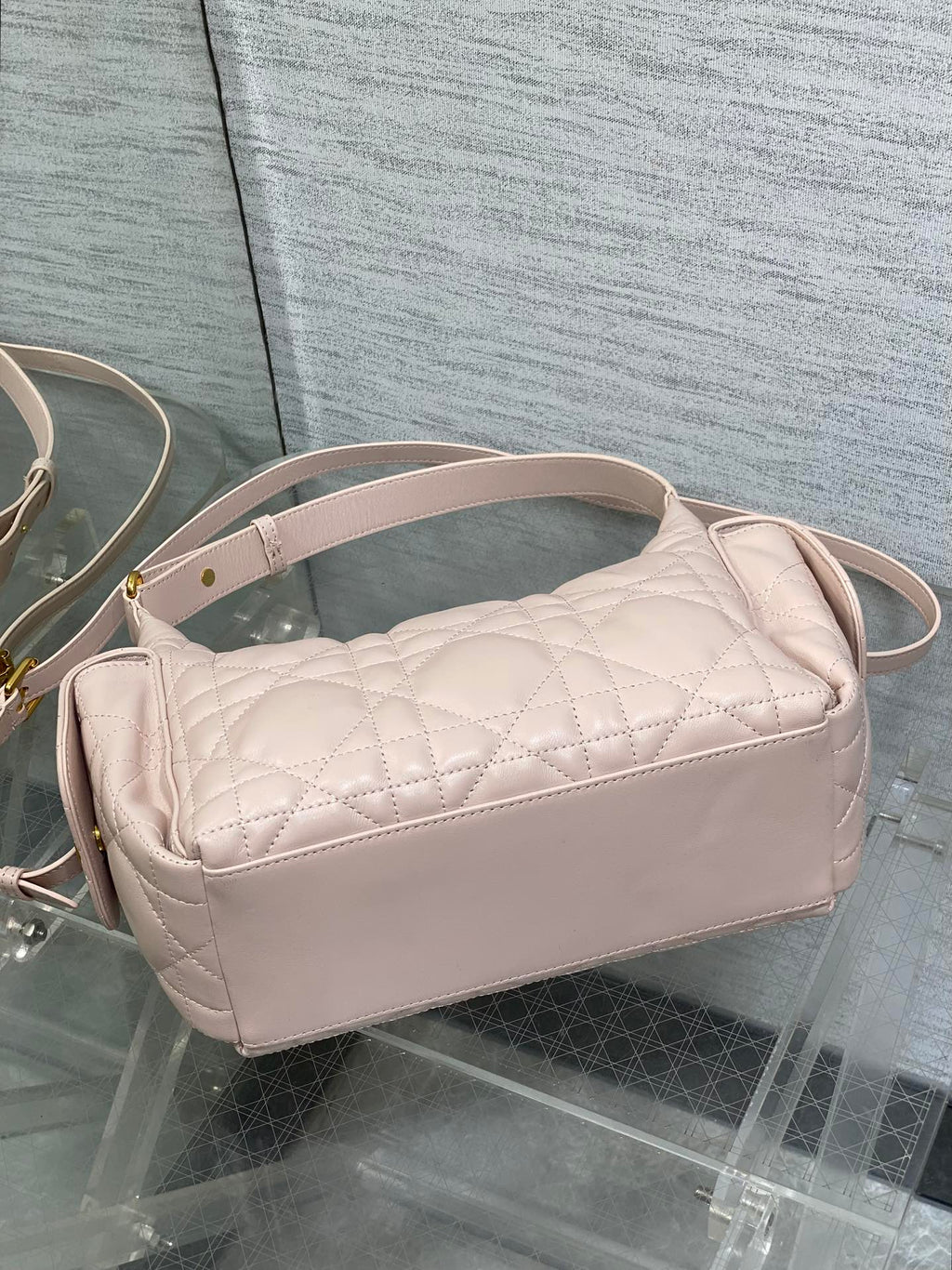 Light pink quilted crossbody bag with curved top and long adjustable strap
