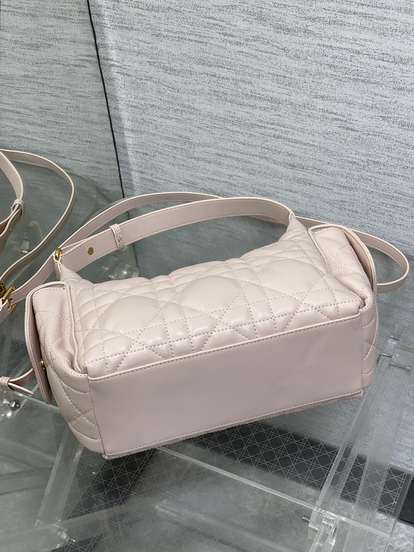 Light pink quilted crossbody bag with curved top and long adjustable strap