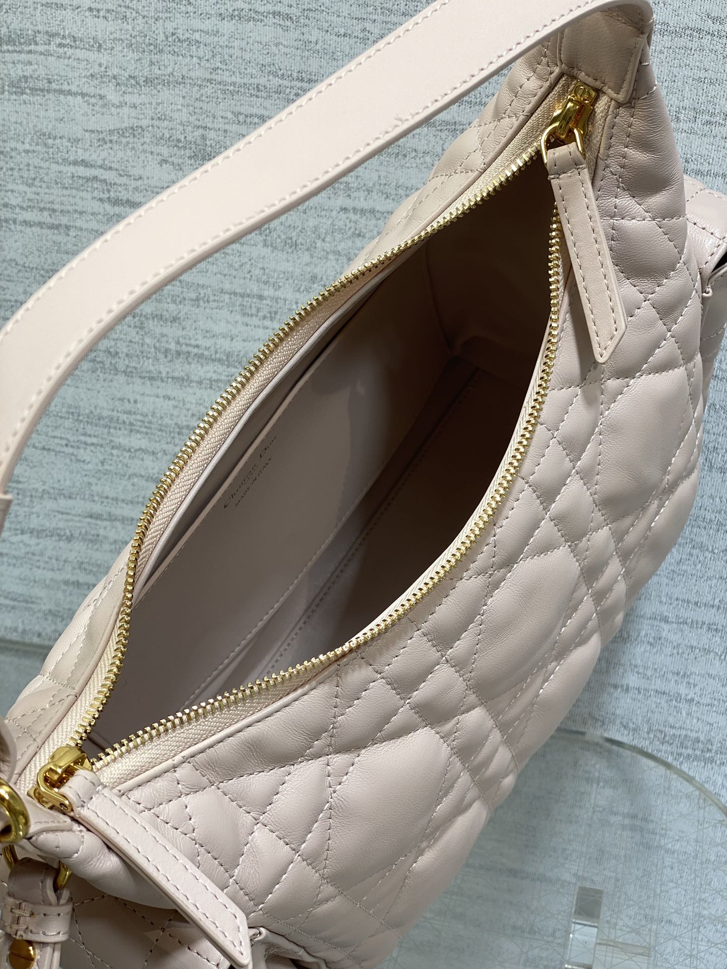 Light pink quilted bag interior with gold zipper and stitched trim