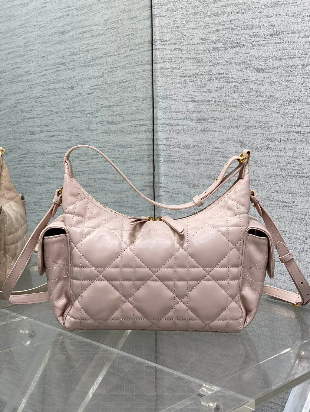 Light pink quilted shoulder bag with adjustable strap and side zipper pockets