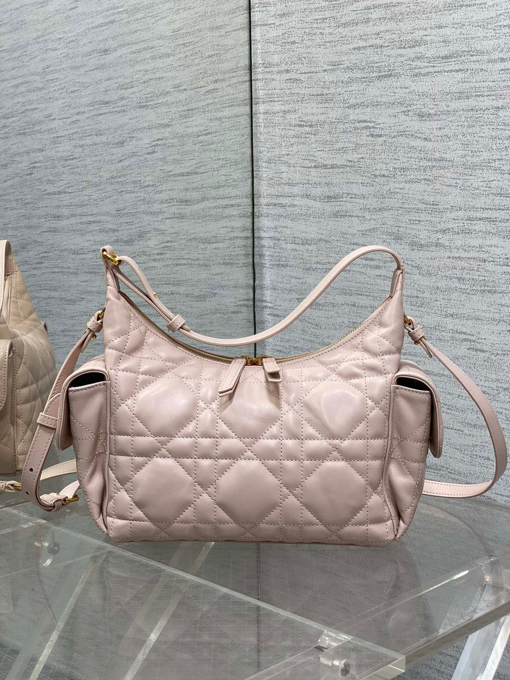 Light pink quilted shoulder bag with curved handle and crossbody strap