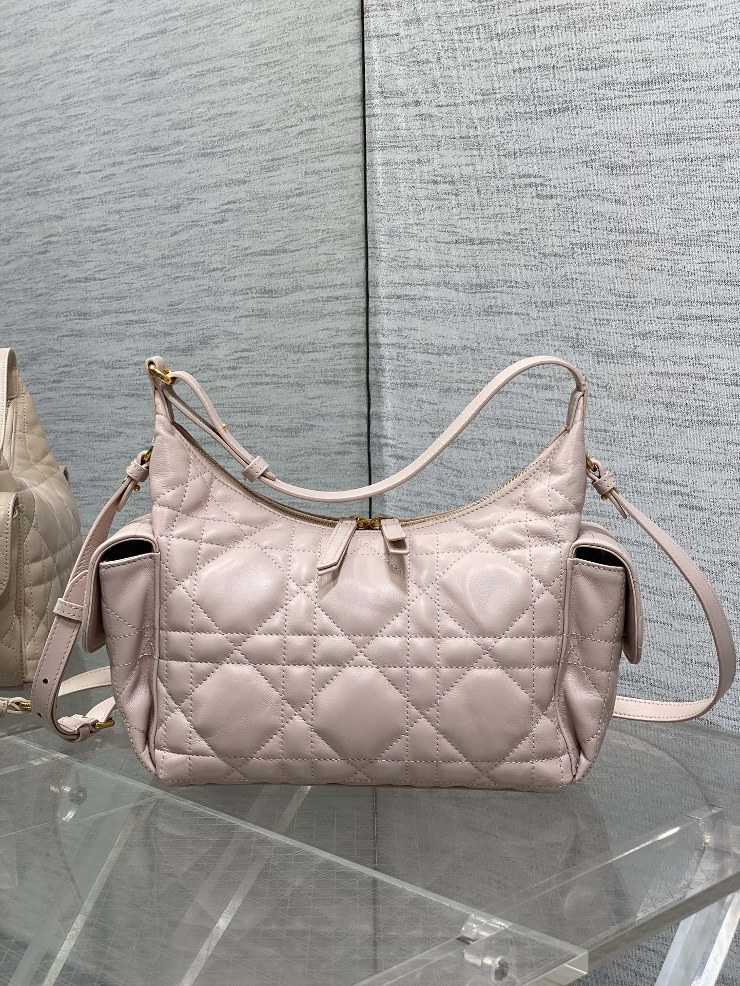 Light pink quilted shoulder bag with curved handle and crossbody strap