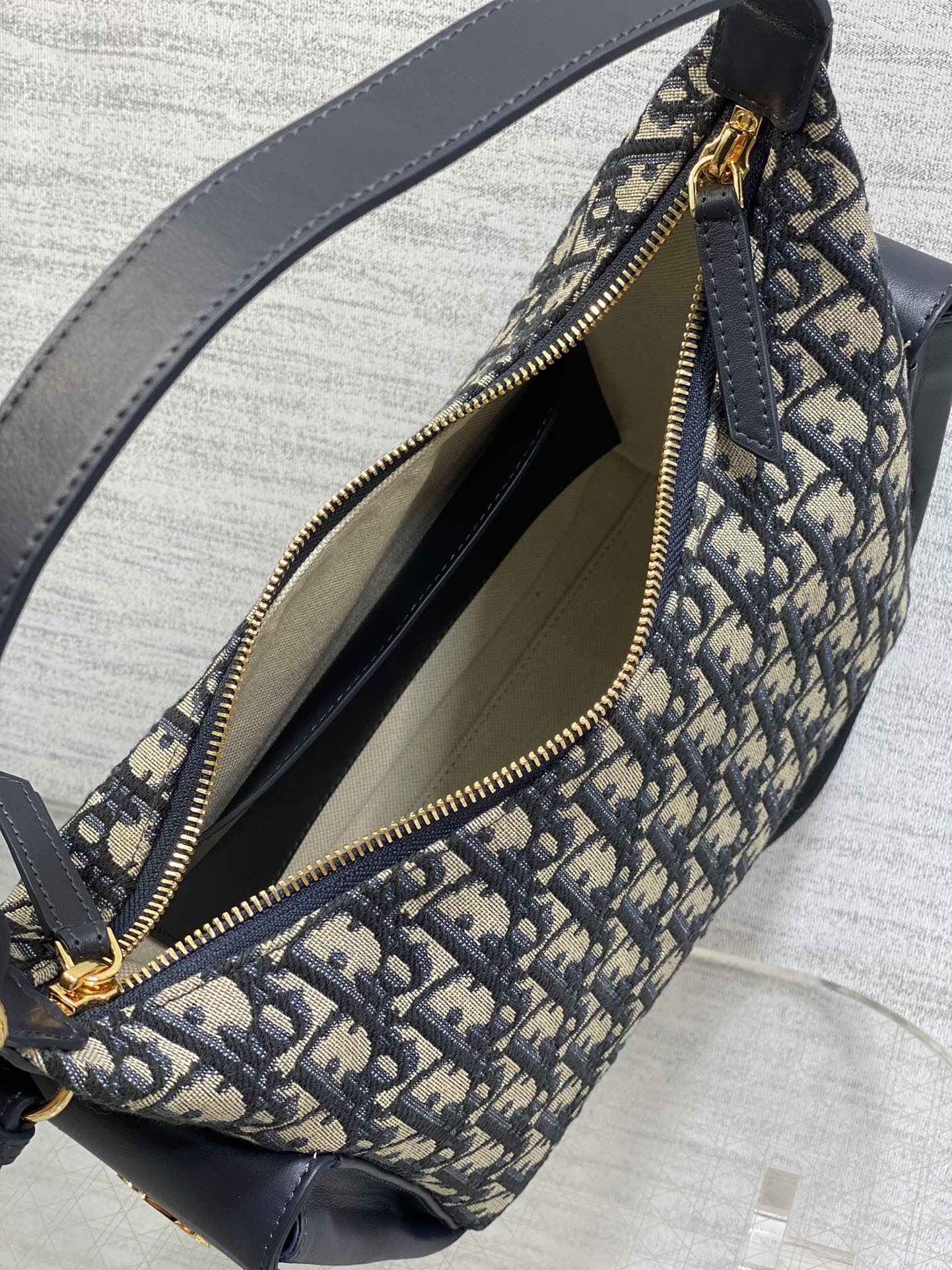 Dior Oblique canvas bag open-top detail with navy lining and gold zipper, close-up
