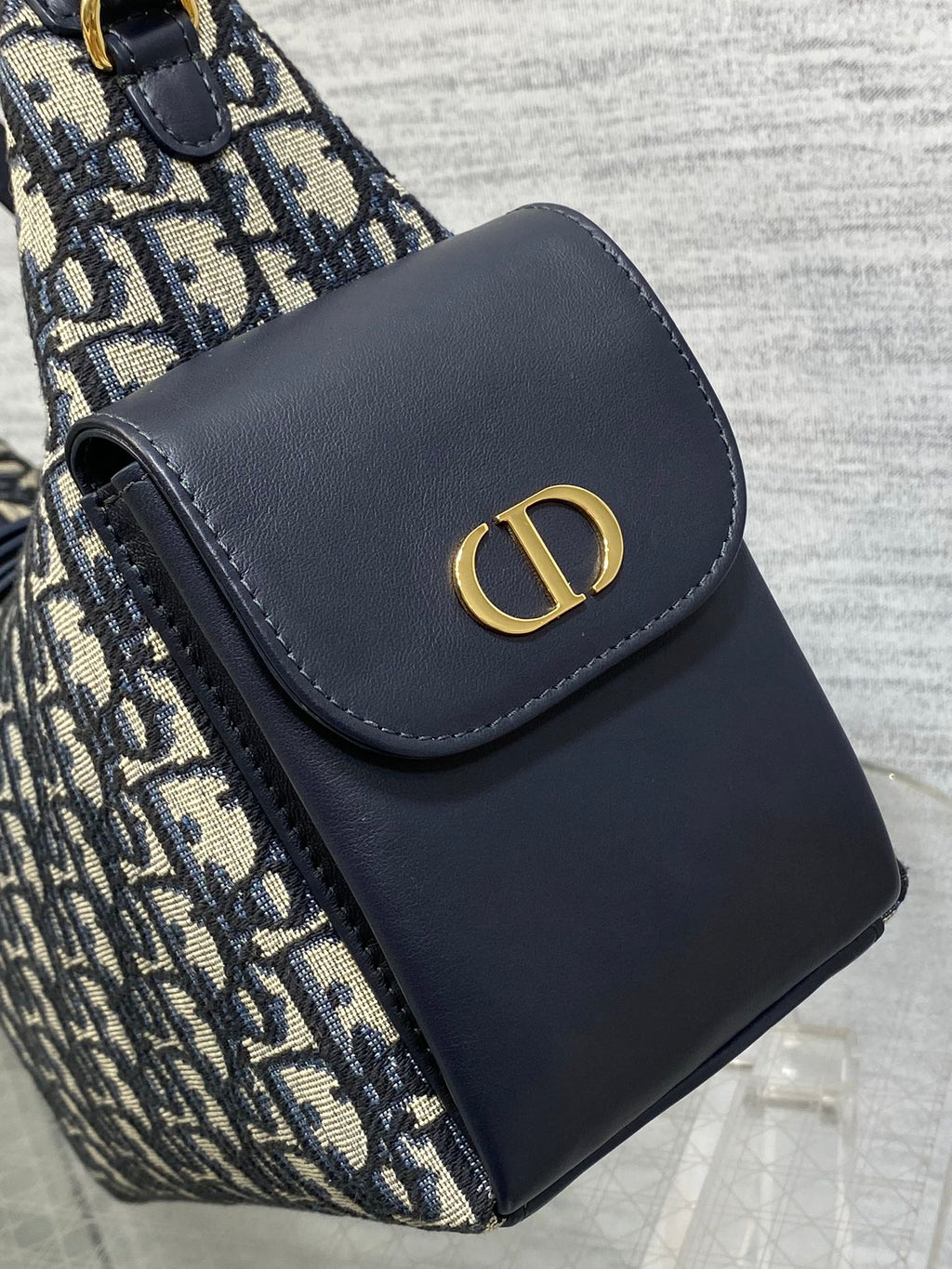 Dior shoulder bag front flap with navy leather and gold CD emblem, close-up