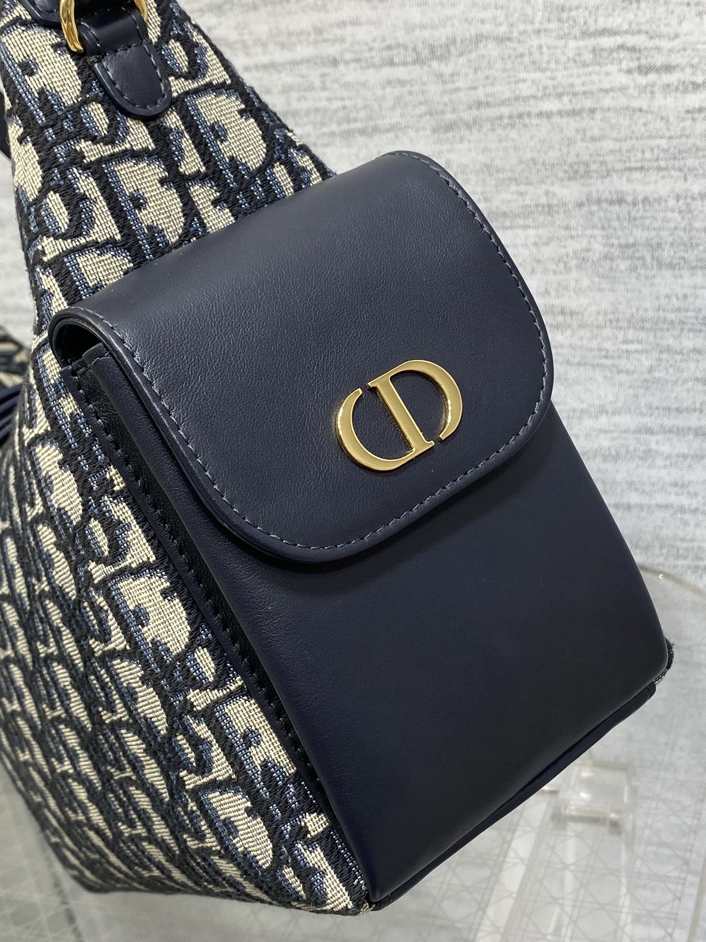 Dior shoulder bag front flap with navy leather and gold CD emblem, close-up