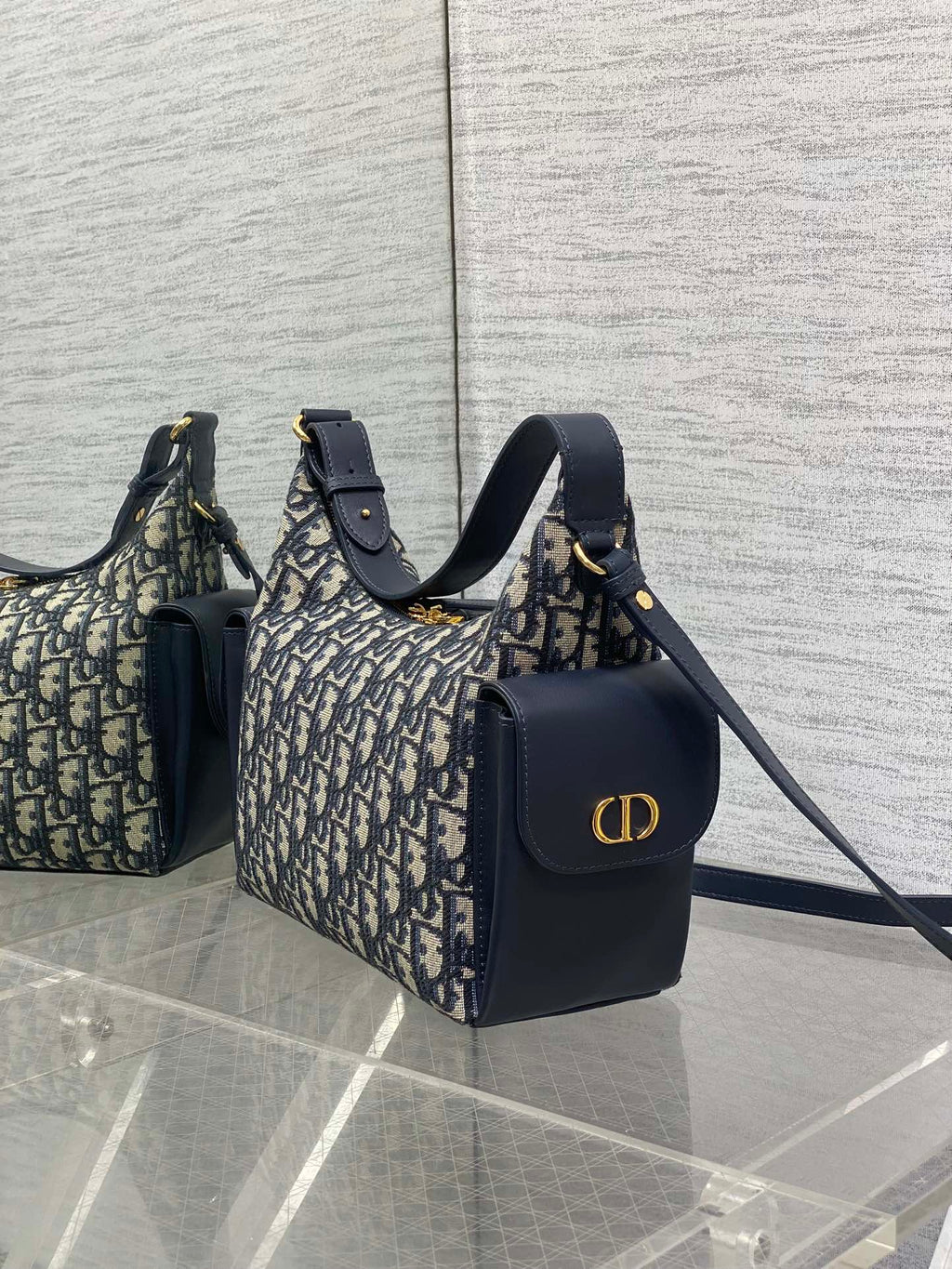 Dior Oblique handbags with navy leather accents, featuring gold CD logo on one bag