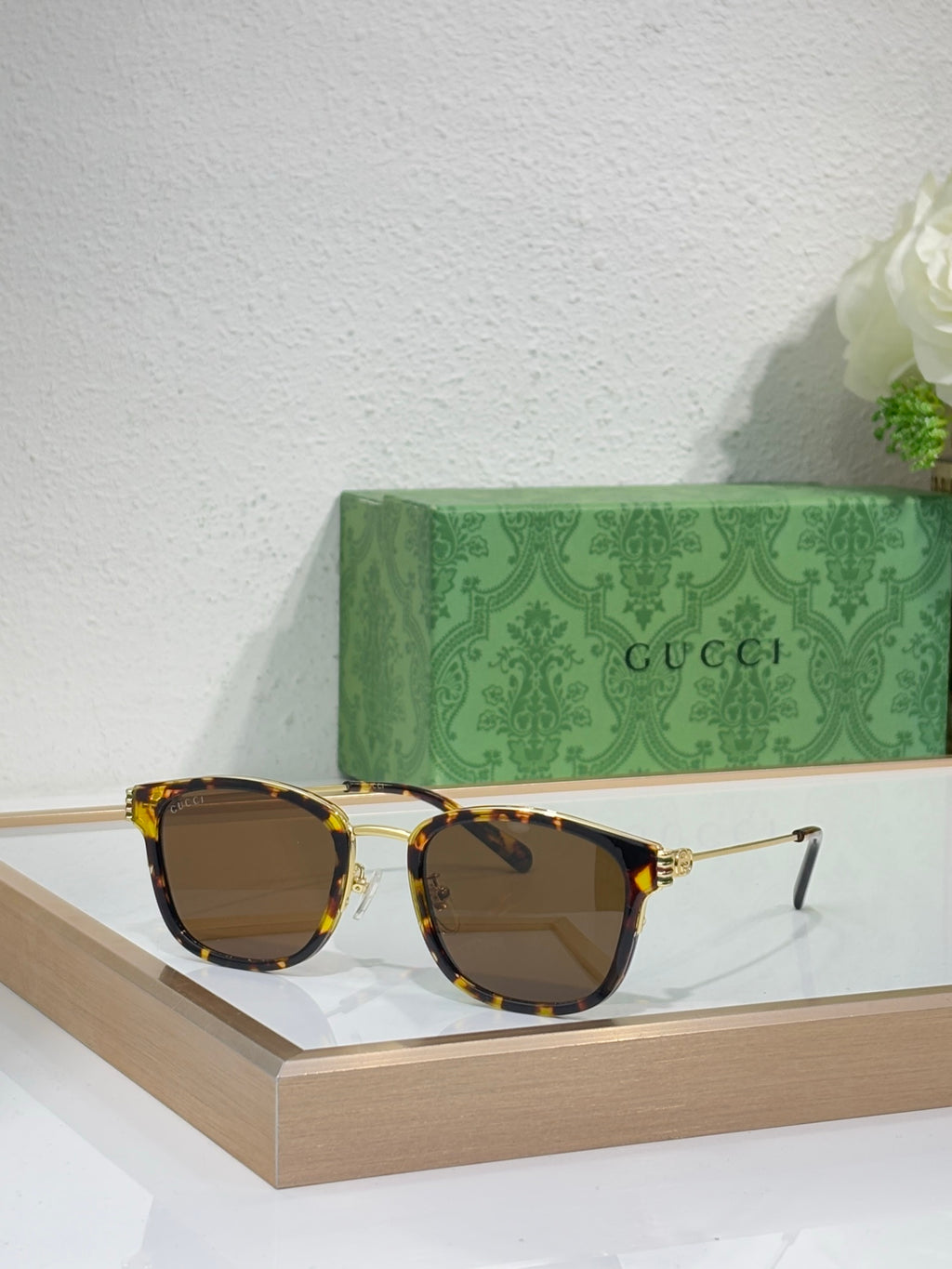 Glasses with tortoiseshell frames, gold accents, and dark brown lenses
