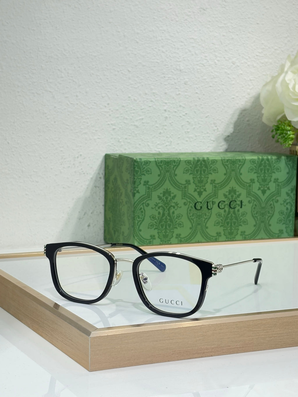 Glasses with black frames, gold accents, and clear lenses with blue tint