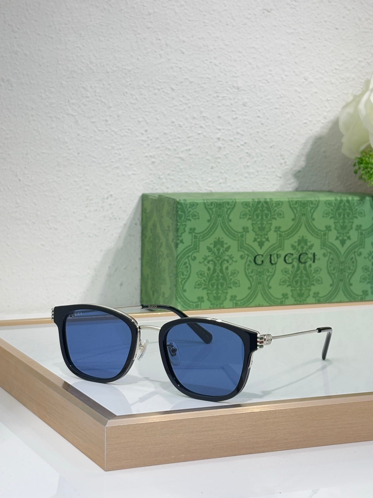 Glasses with dark blue lenses and black rectangular frames with gold accents