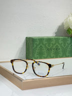 Glasses with tortoiseshell frames, gold hinges, and clear lenses