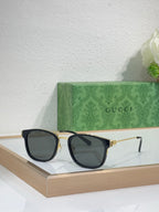 Glasses with black frames, gold hinges, and dark gray lenses