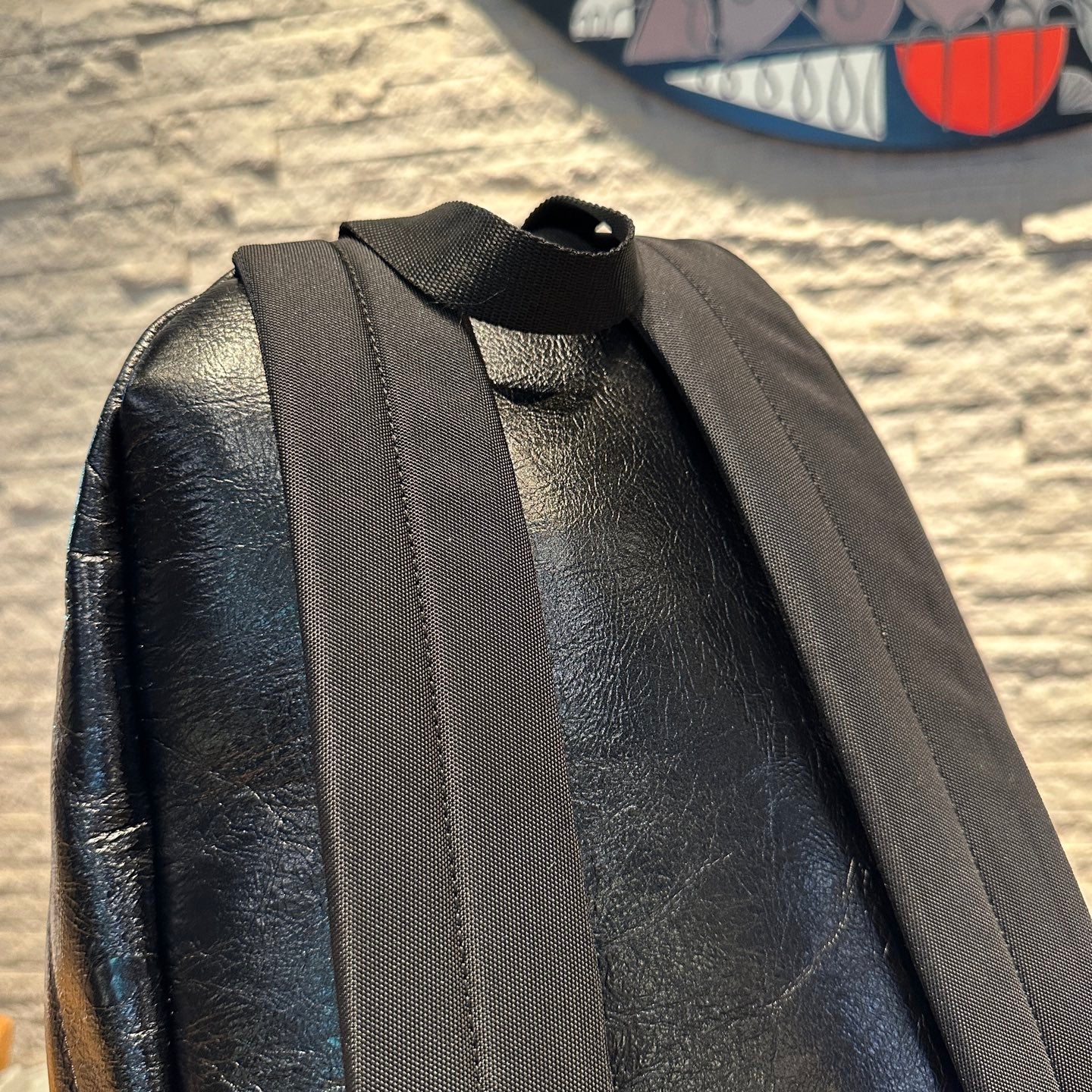 Black leather backpack back panel with wide webbing shoulder straps