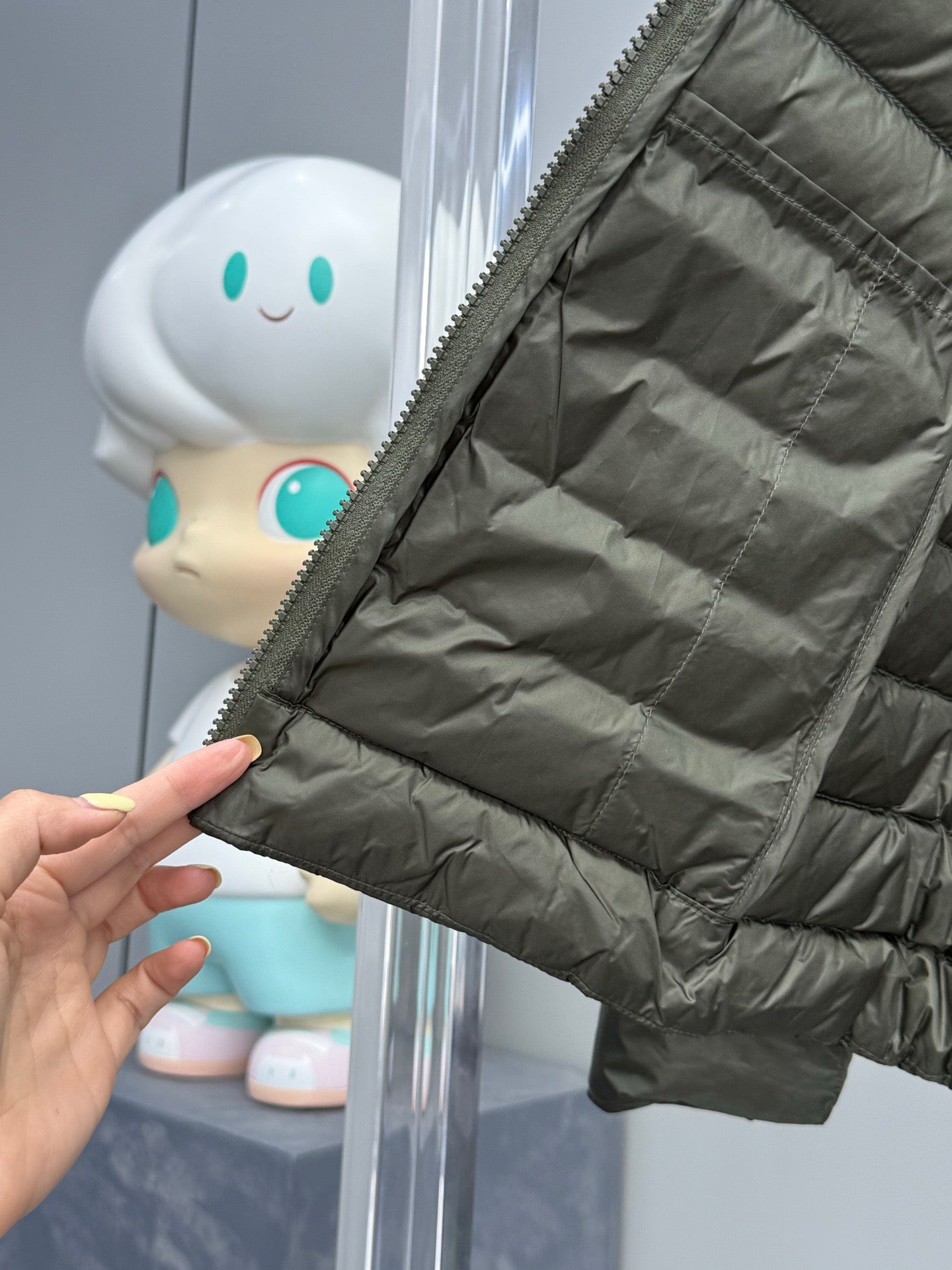 Dark green puffer jacket sleeve with elastic cuff and stitched quilting.
