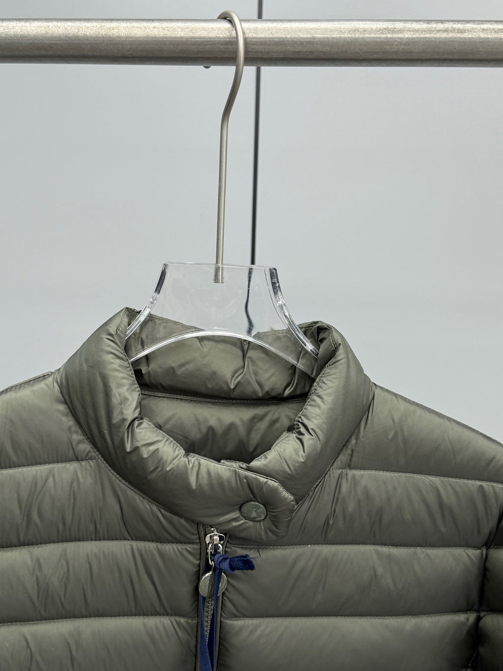 Olive puffer jacket with quilted panels and inner collar.
