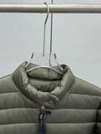 Olive puffer jacket with quilted panels and inner collar.
