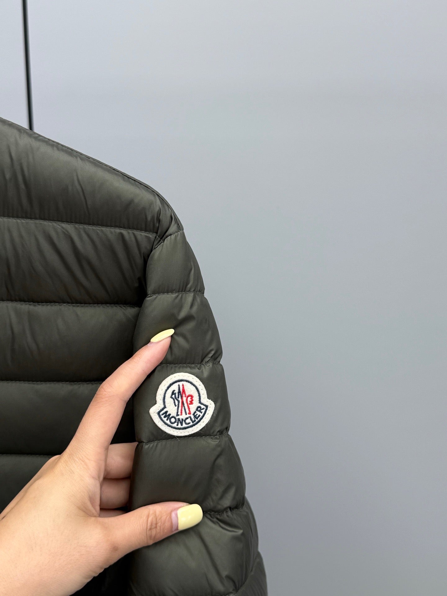 Dark puffer jacket sleeve with circular Moncler patch.