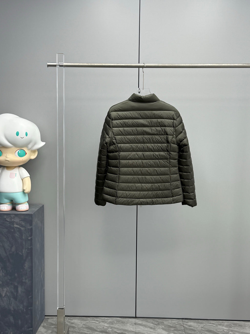 Dark puffer jacket on hanger with full zipper and long sleeves.