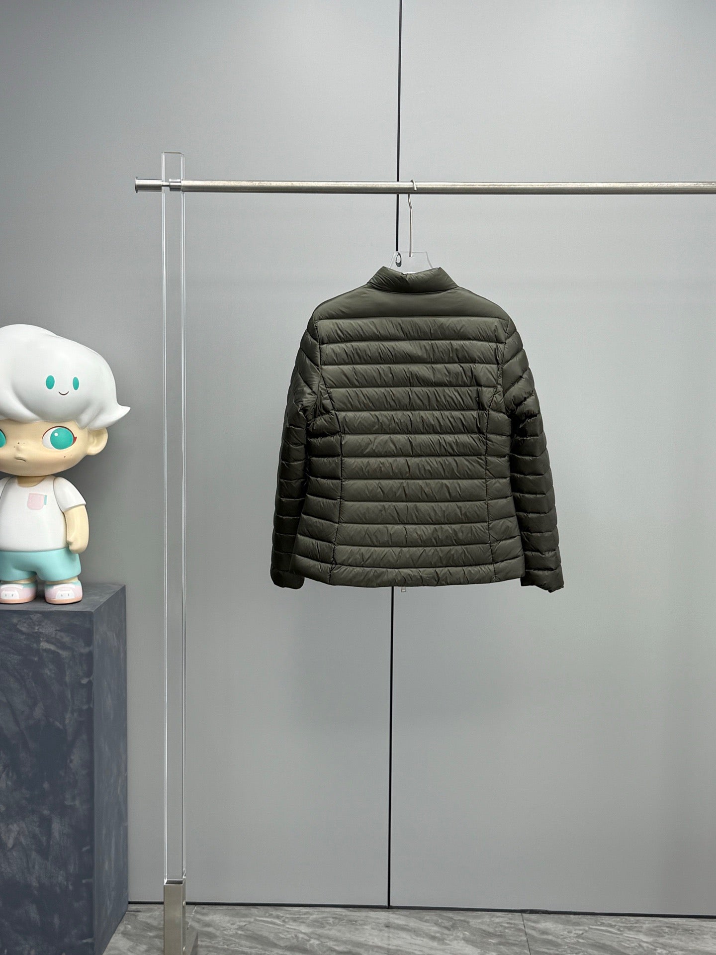 Dark puffer jacket on hanger with full zipper and long sleeves.