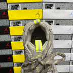 Gray sneaker opening with neon yellow striped fabric tab on the tongue