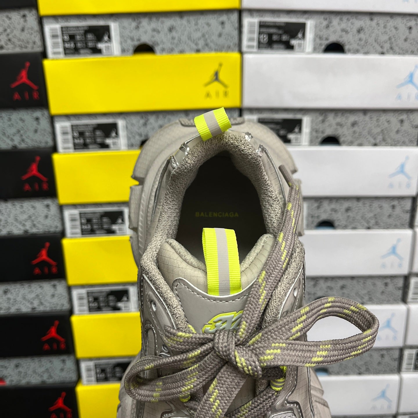 Gray sneaker opening with neon yellow striped fabric tab on the tongue