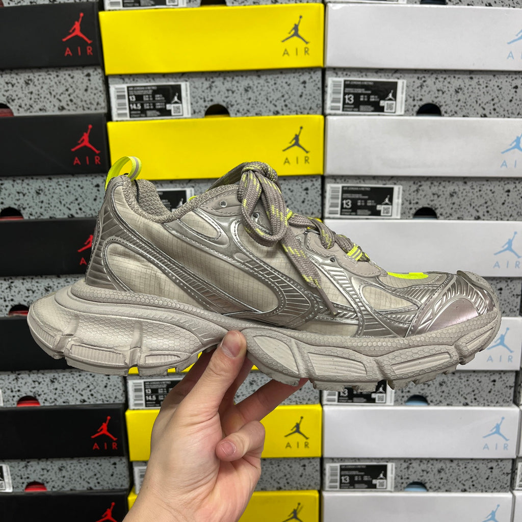 Silver gray sneaker side view with neon yellow accents and chunky shock-absorb sole