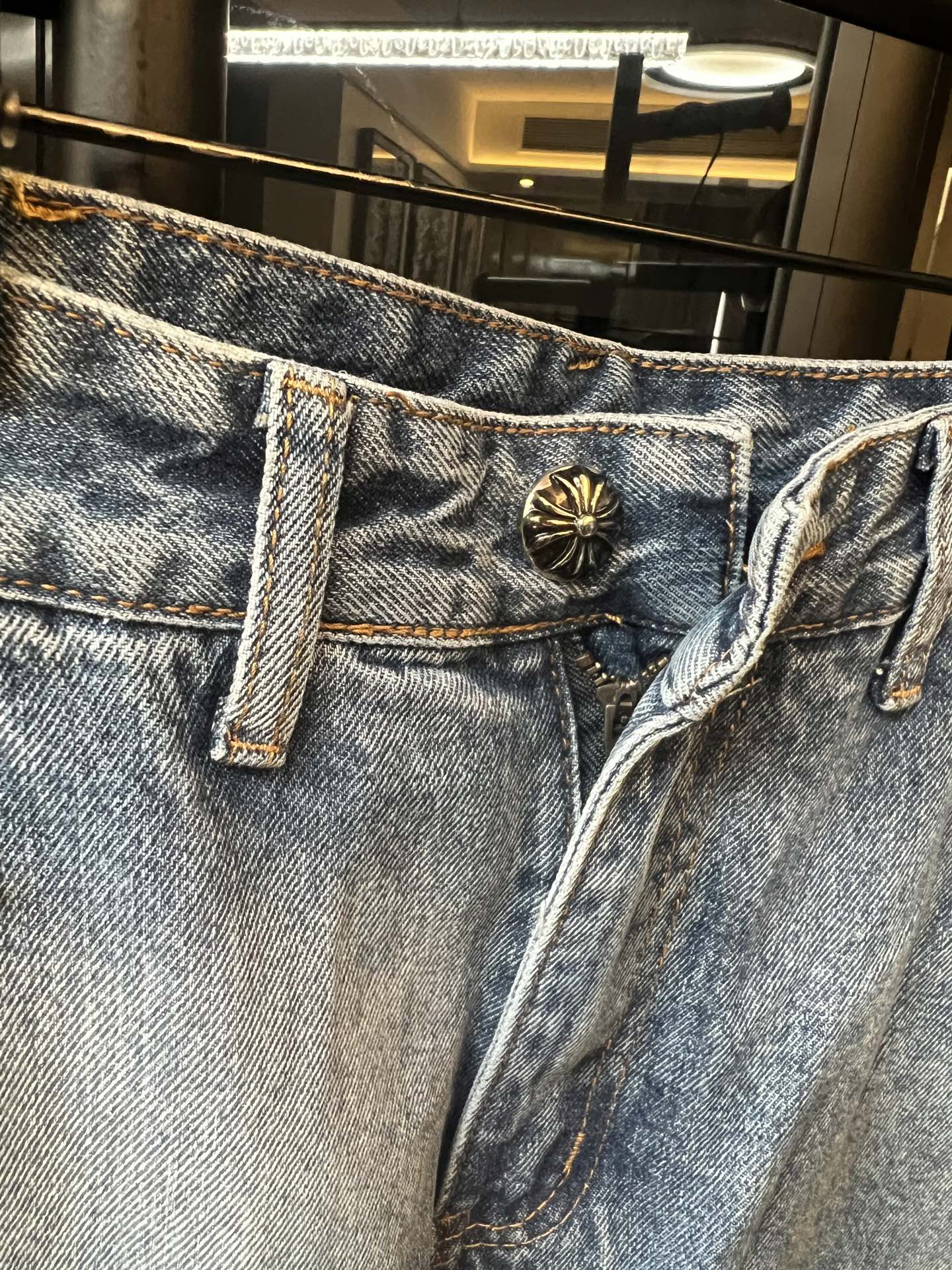 Light blue denim pants with belt loops and ornate button fly front