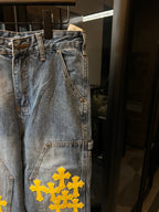 Light blue denim pants with yellow cross embroidery on front leg