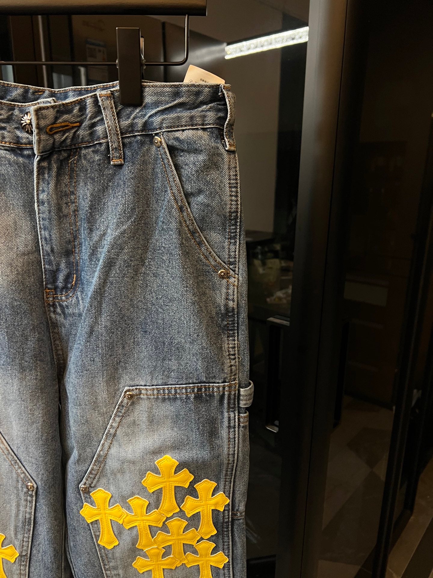 Light blue denim pants with yellow cross embroidery on front leg