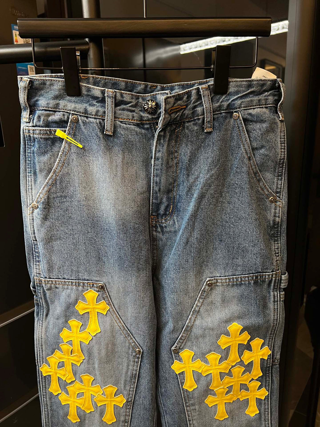 Light blue denim pants with yellow cross embroidery on pockets and thighs