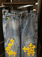 Light blue denim pants with yellow cross embroidery on pockets and thighs