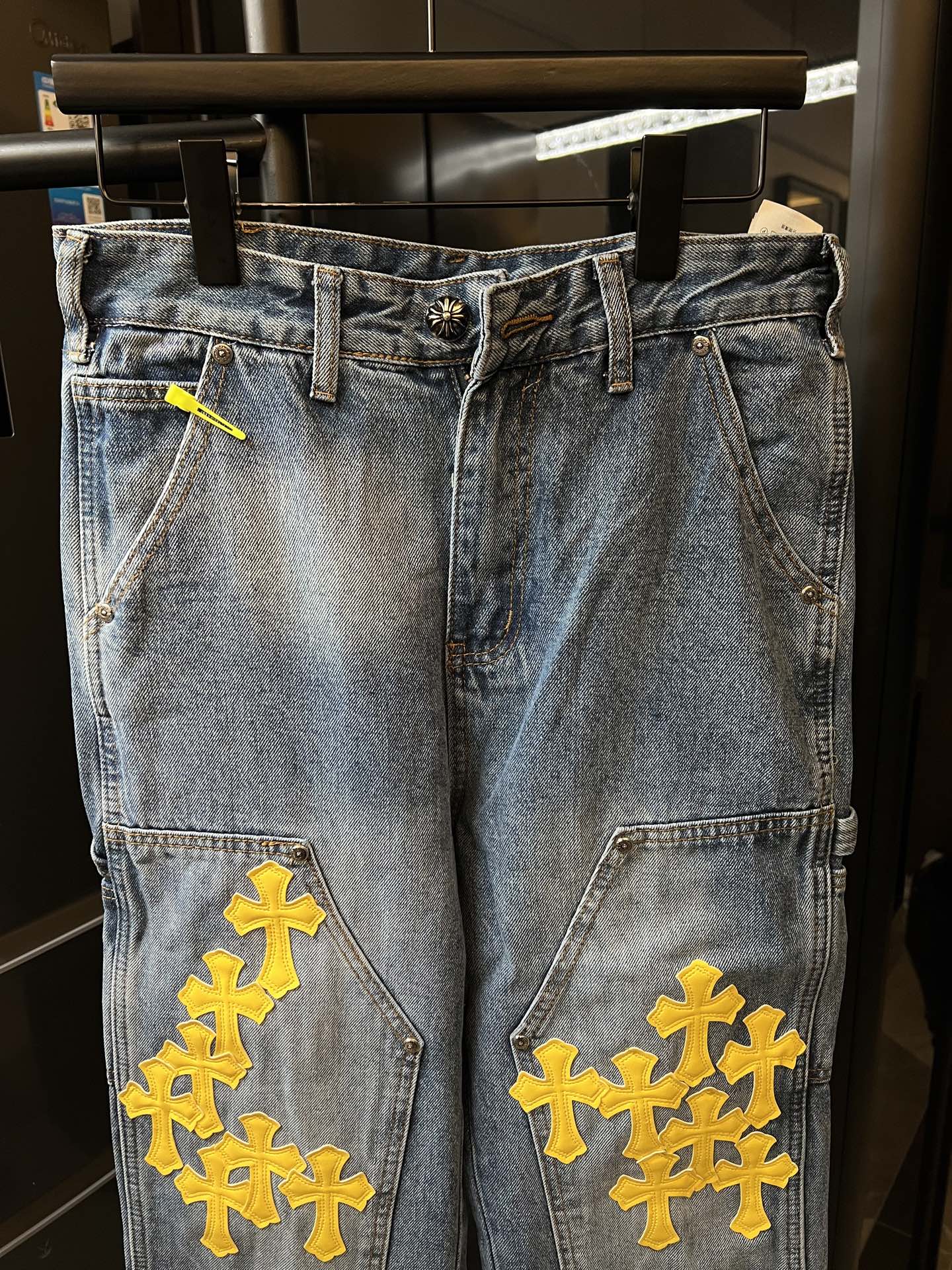 Light blue denim pants with yellow cross embroidery on pockets and thighs