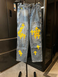 Light blue denim pants with yellow cross embroidery on the legs