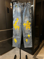 Light blue denim pants with yellow cross embroidery on the legs