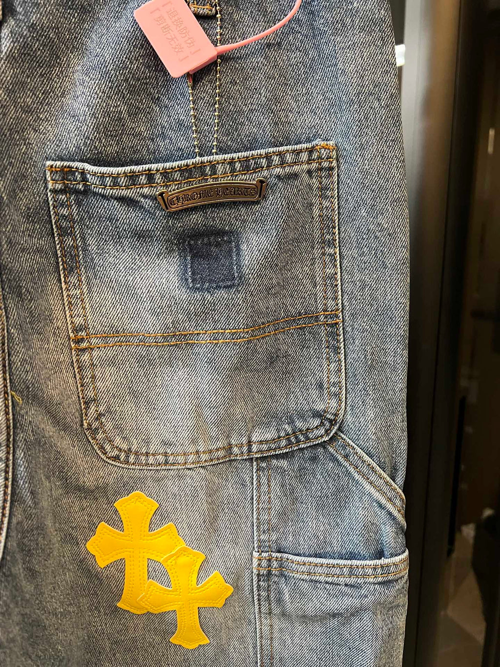Light blue denim pants with front pocket label and yellow cross patch