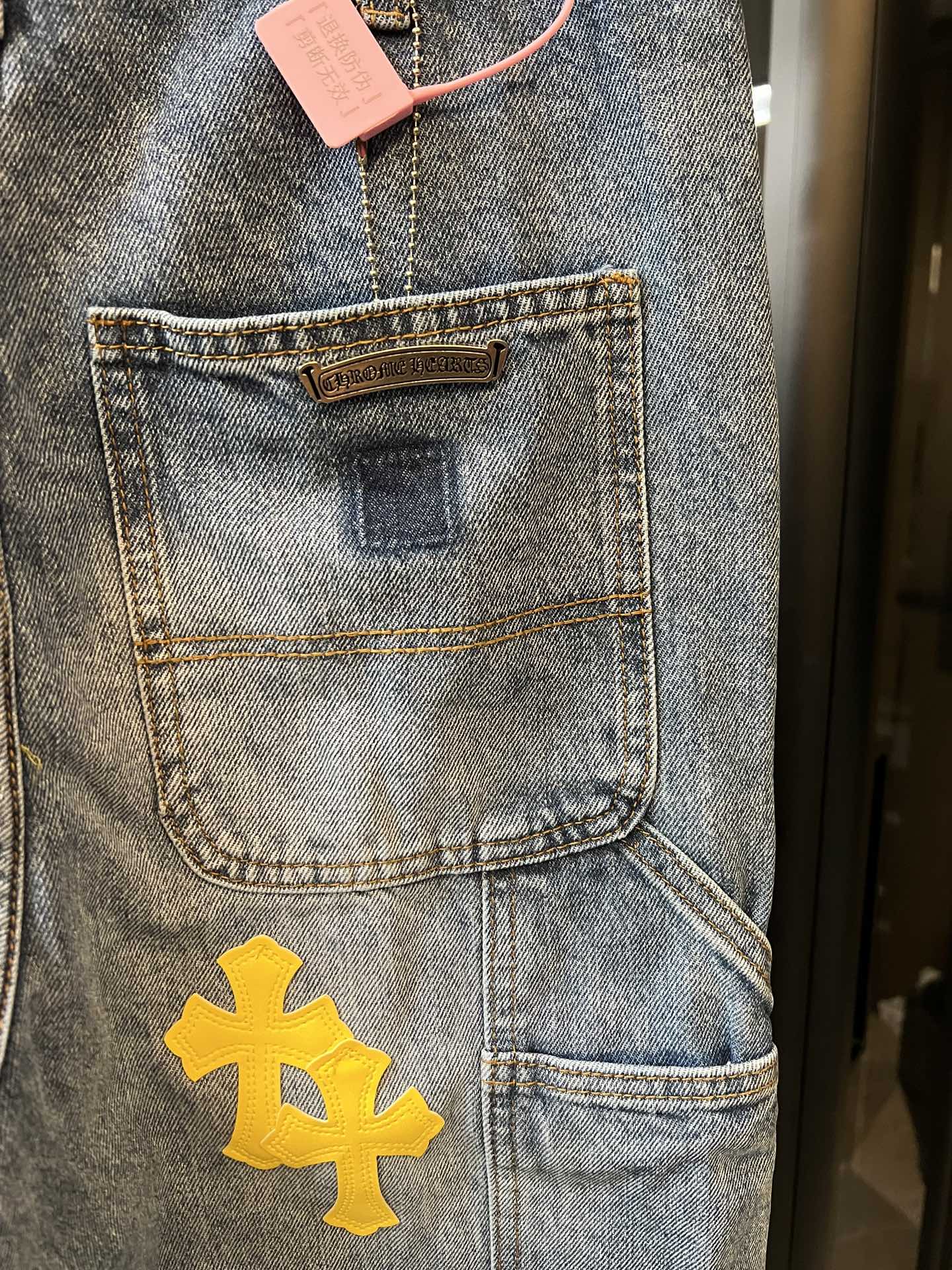Light blue denim pants with front pocket label and yellow cross patch