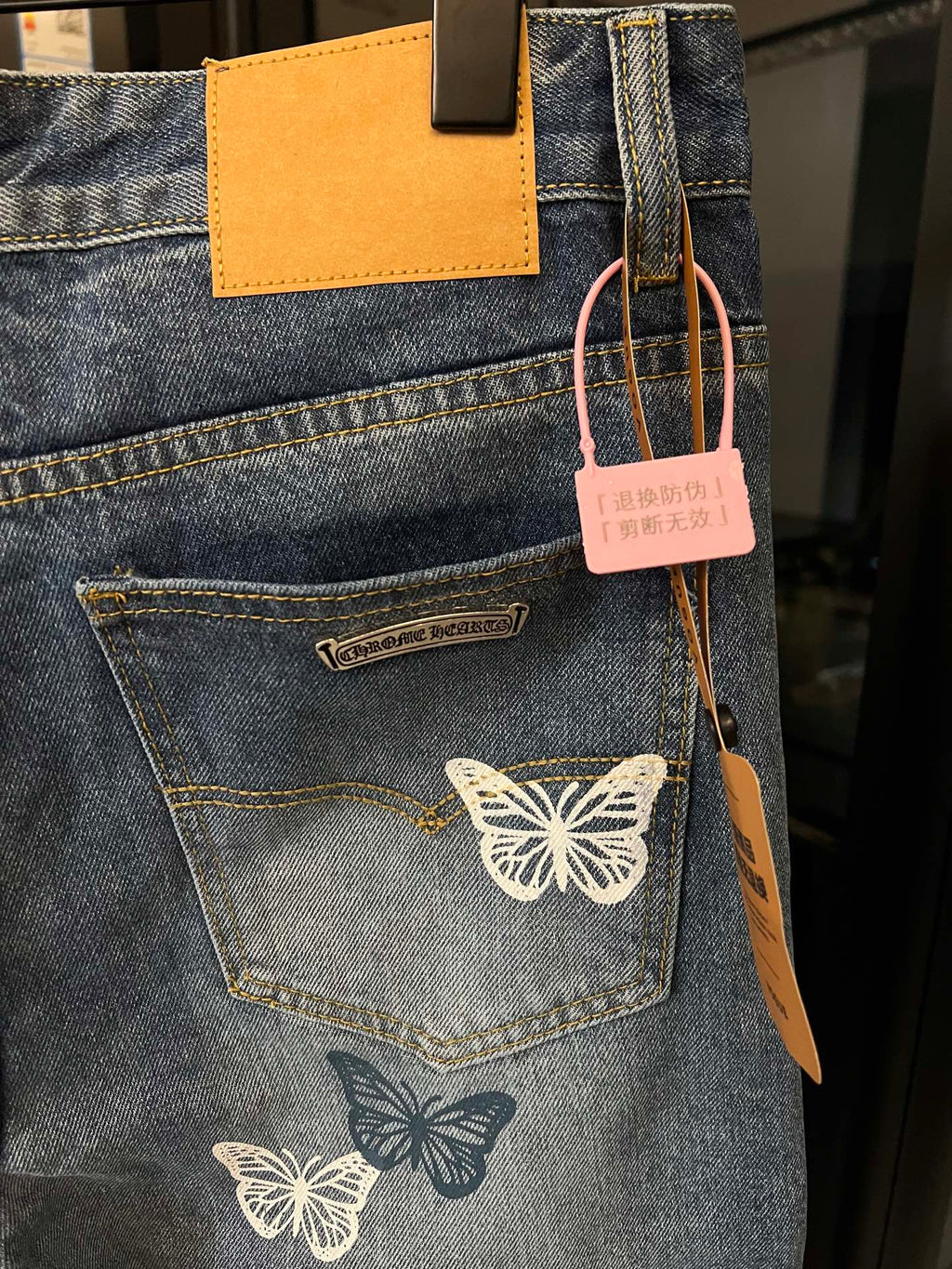 Blue denim pants with butterfly embroidery, visible rear pocket and leather logo tab