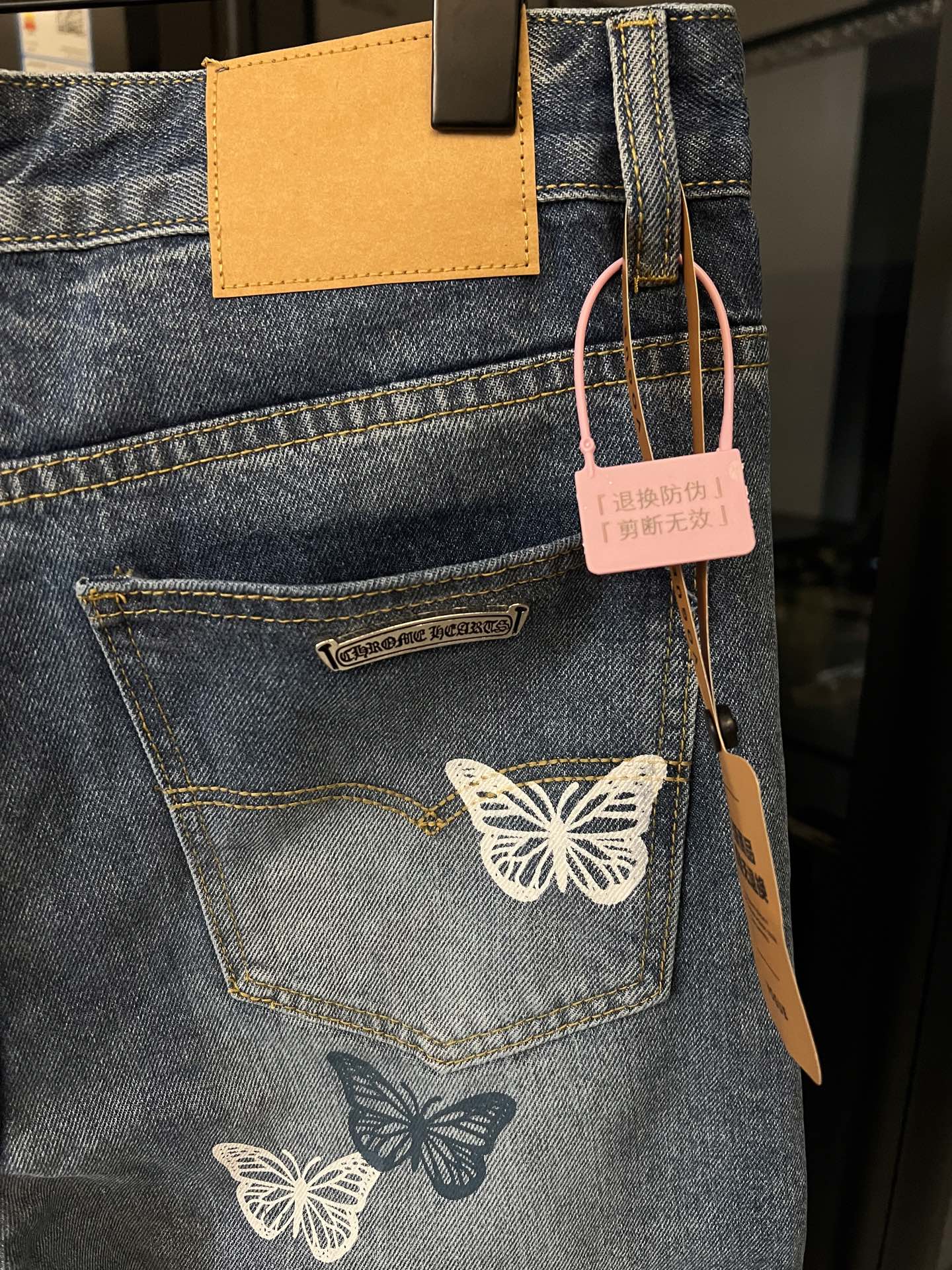 Blue denim pants with butterfly embroidery, visible rear pocket and leather logo tab