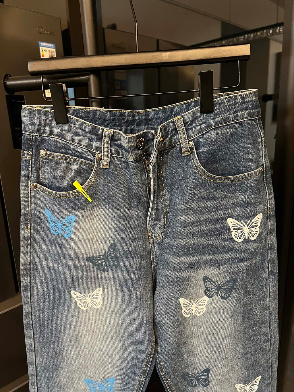 Blue denim pants with butterfly patches, front zipper fly, and curved back yoke pocket