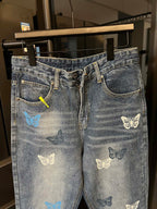 Blue denim pants with butterfly patches, front zipper fly, and curved back yoke pocket