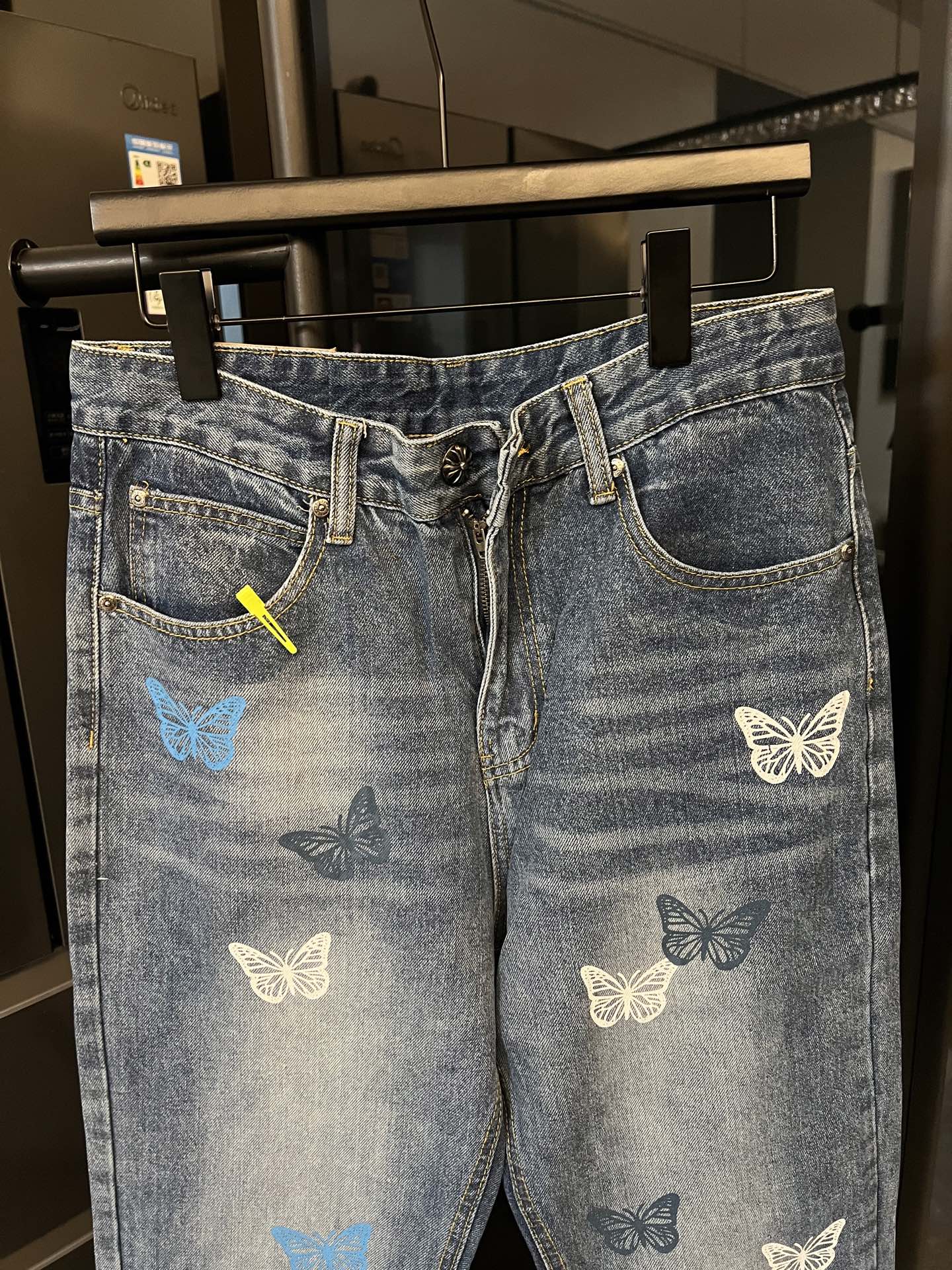 Blue denim pants with butterfly patches, front zipper fly, and curved back yoke pocket