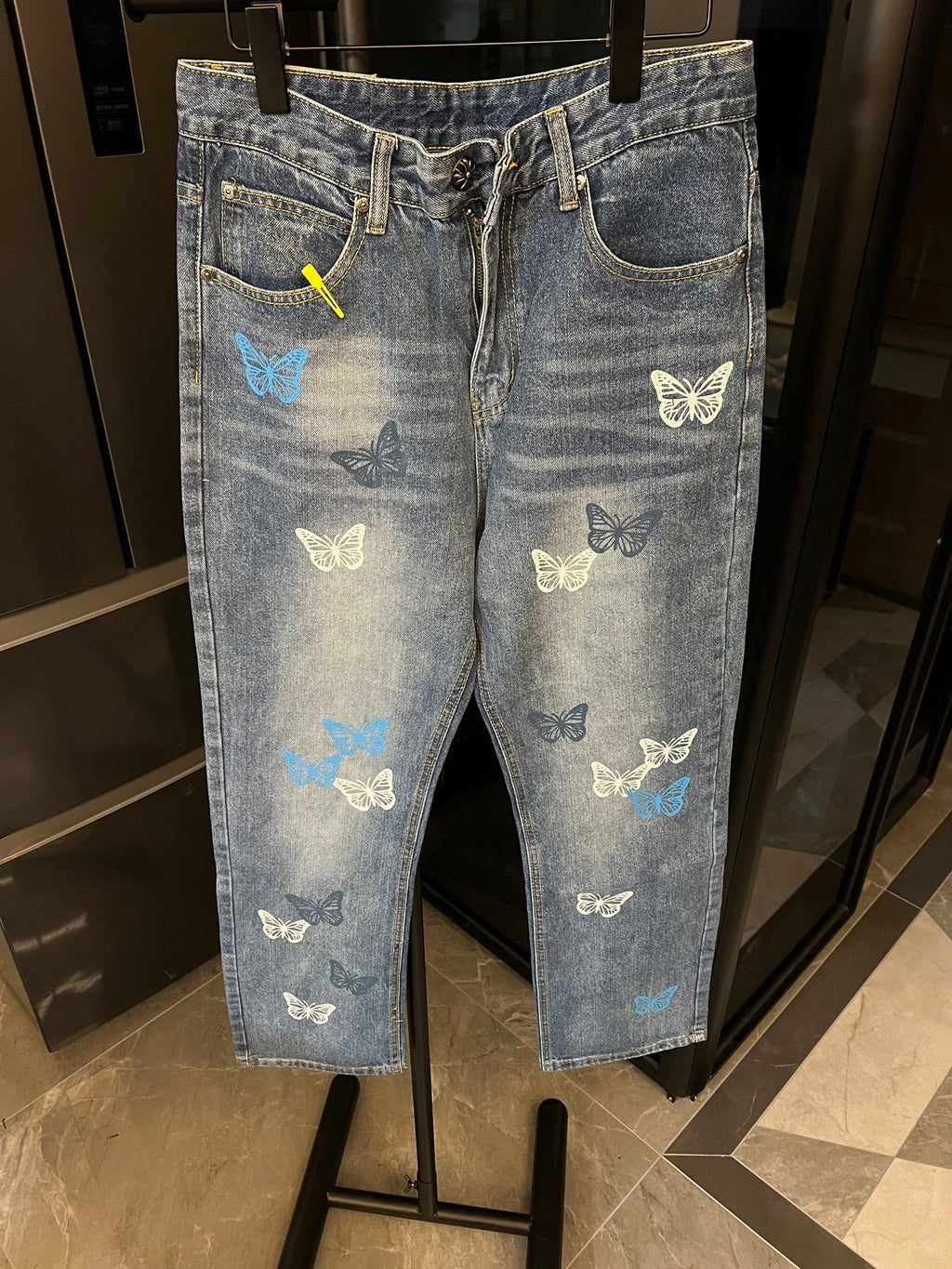 Light-wash denim pants with butterfly patches, front zipper, and side seam pockets