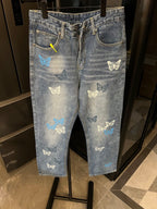Light-wash denim pants with butterfly patches, front zipper, and side seam pockets