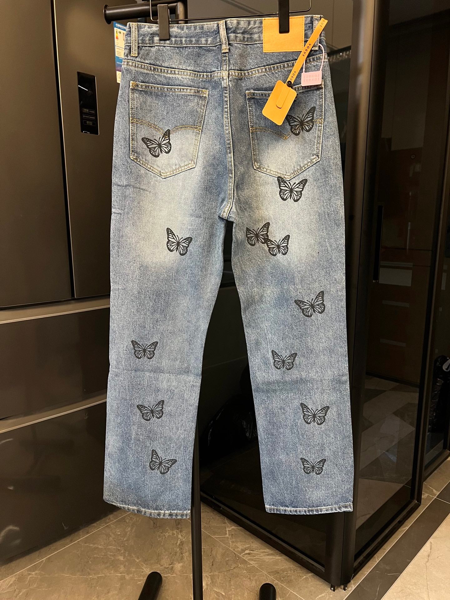 Light blue denim jeans with black butterfly embroidery and front pockets, hanging tags attached
