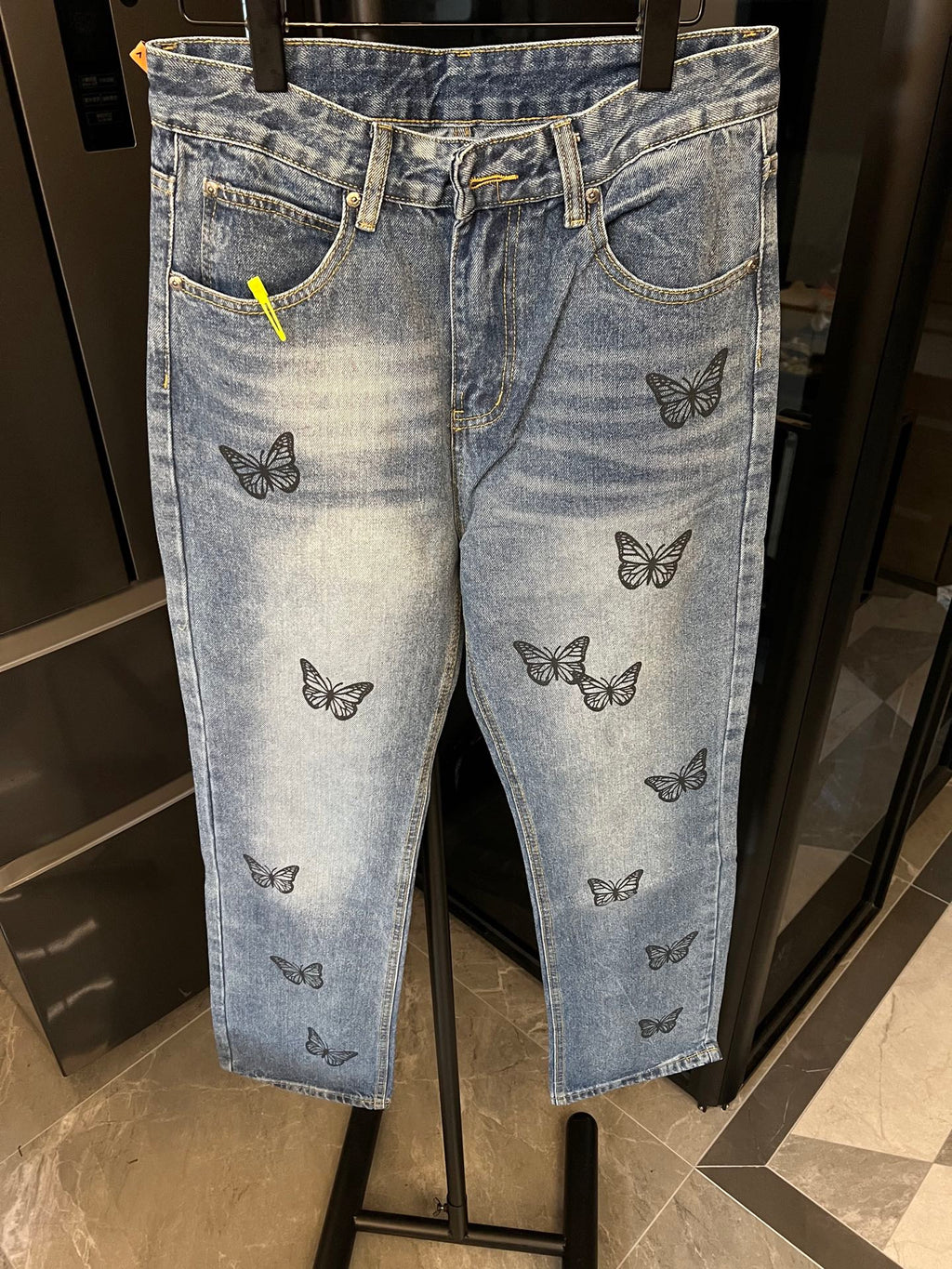 Light blue denim pants with black butterfly embroidery on legs and waistband